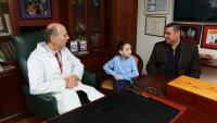 Dr. Neil A. Feldstein sits in his office with young patient and patient's parent